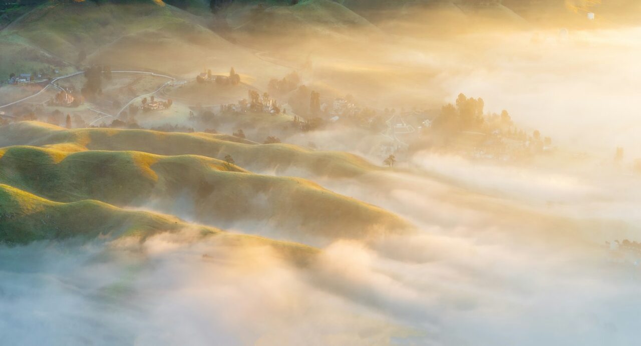 Sunrise over hills wrapped in morning mist.