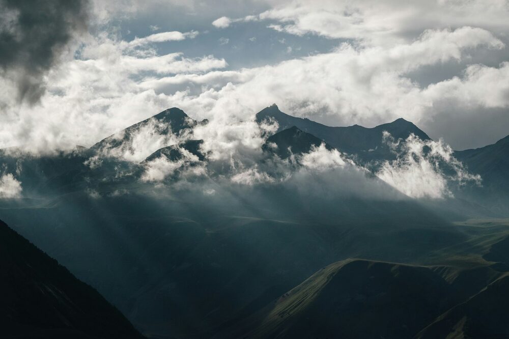 Sunlight breaking through clouds over mountain peaks.