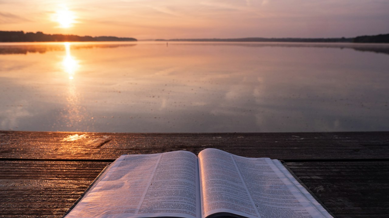 An open Bible resting on a wooden table.